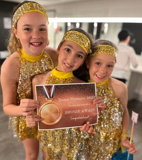 Three students holding Dance Olympics award